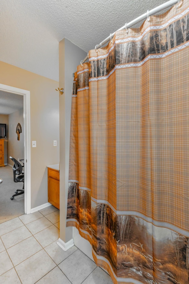 bathroom with a textured ceiling, tile patterned flooring, a shower with shower curtain, vanity, and baseboards