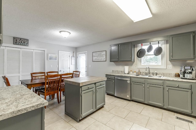 kitchen with light countertops, a sink, a kitchen island, and stainless steel dishwasher