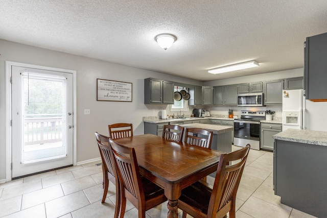 dining area featuring a healthy amount of sunlight, light tile patterned floors, baseboards, and a textured ceiling