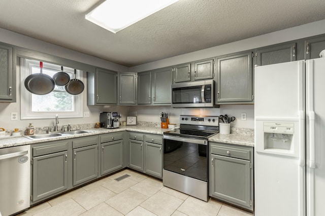 kitchen with visible vents, appliances with stainless steel finishes, gray cabinets, light countertops, and a sink