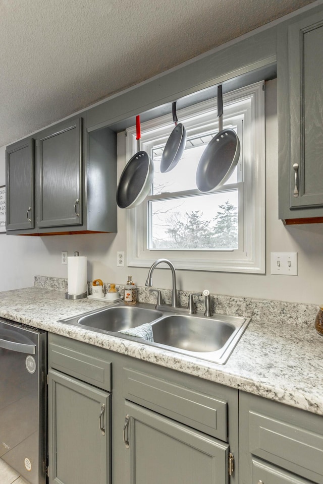 kitchen featuring a sink, a textured ceiling, light countertops, and dishwasher