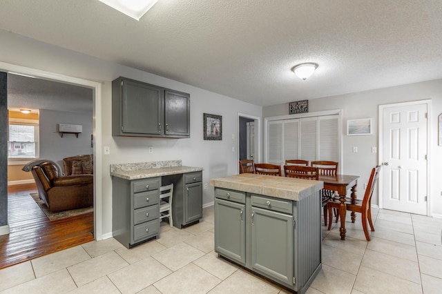 kitchen featuring light tile patterned floors, light countertops, a kitchen island, a textured ceiling, and baseboards