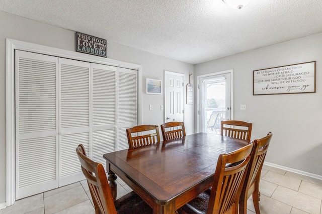 dining space featuring light tile patterned floors, a textured ceiling, and baseboards