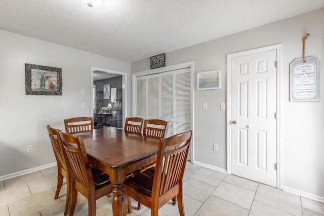 dining room featuring light tile patterned floors, a textured ceiling, and baseboards