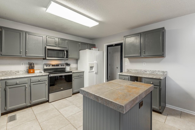 kitchen featuring visible vents, appliances with stainless steel finishes, gray cabinets, and a center island