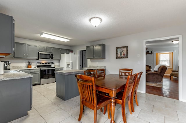 dining area with a textured ceiling, light tile patterned flooring, and baseboards