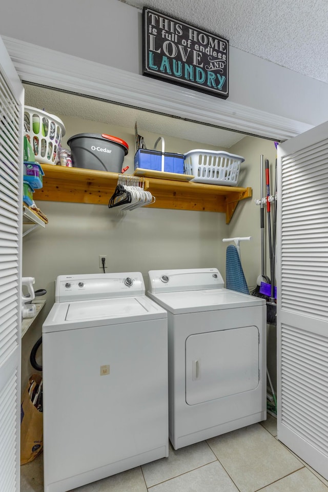 laundry area with laundry area, a textured ceiling, washing machine and clothes dryer, and light tile patterned floors