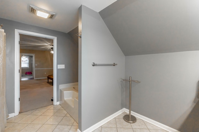 bathroom with tile patterned floors, visible vents, baseboards, vaulted ceiling, and a tub