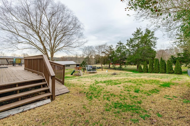 view of yard featuring a trampoline, a playground, and a deck