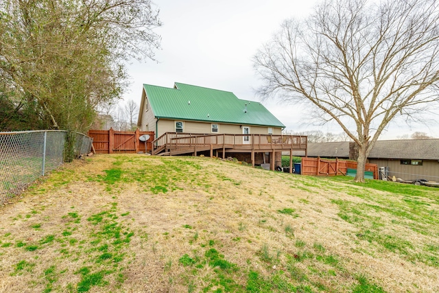 back of property featuring a fenced backyard, metal roof, a gate, a deck, and a yard