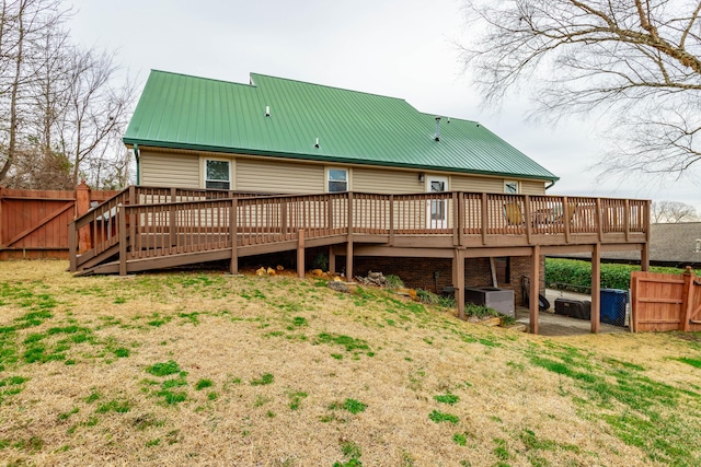 rear view of house with a deck, metal roof, and fence