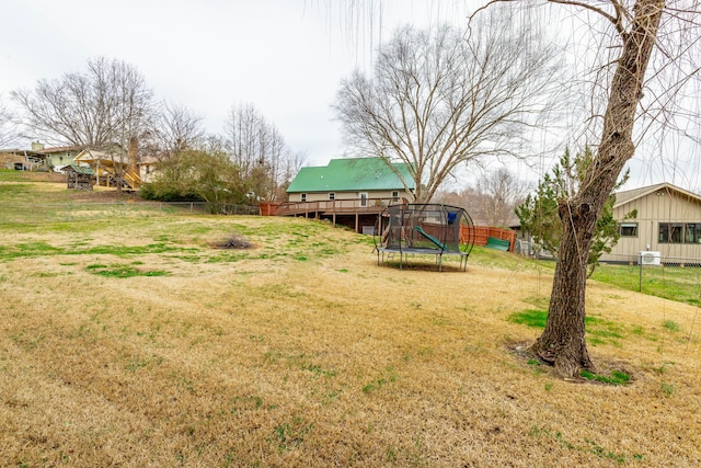 view of yard with a trampoline and a wooden deck