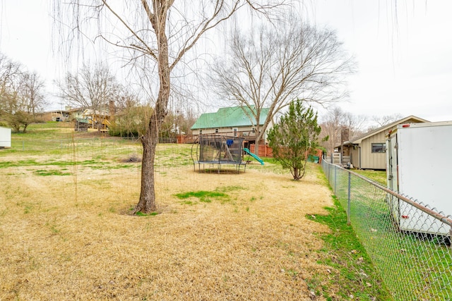 view of yard featuring a trampoline, a fenced backyard, and a playground