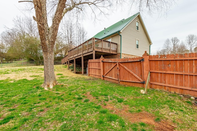 rear view of property with a yard, a gate, metal roof, fence private yard, and a wooden deck