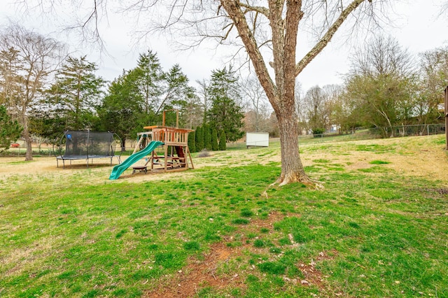 view of yard featuring a trampoline, fence, and a playground