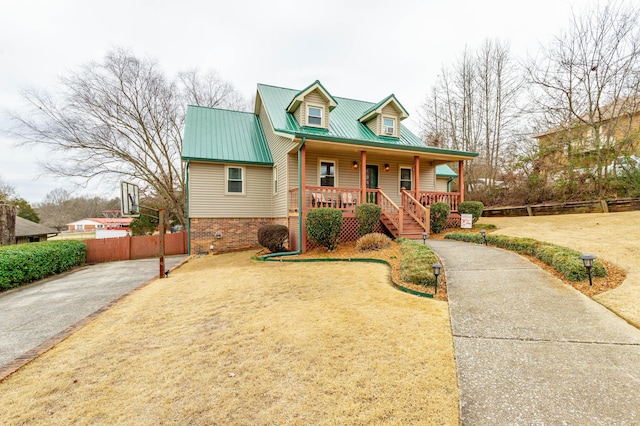 view of front of property with covered porch, metal roof, fence, and a front lawn