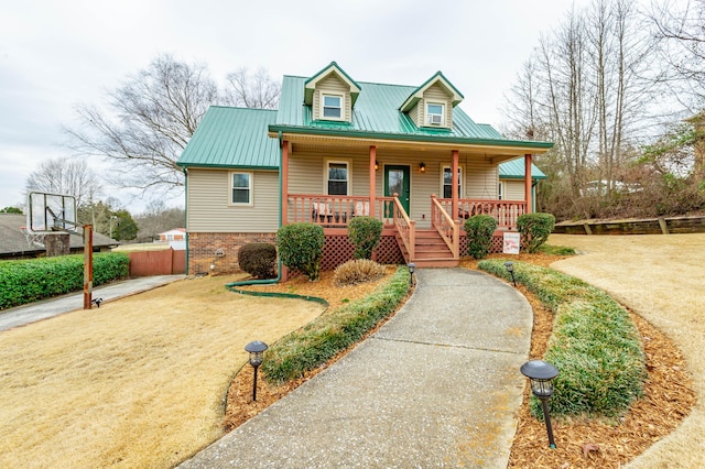 view of front of home with brick siding, metal roof, a porch, and a front yard