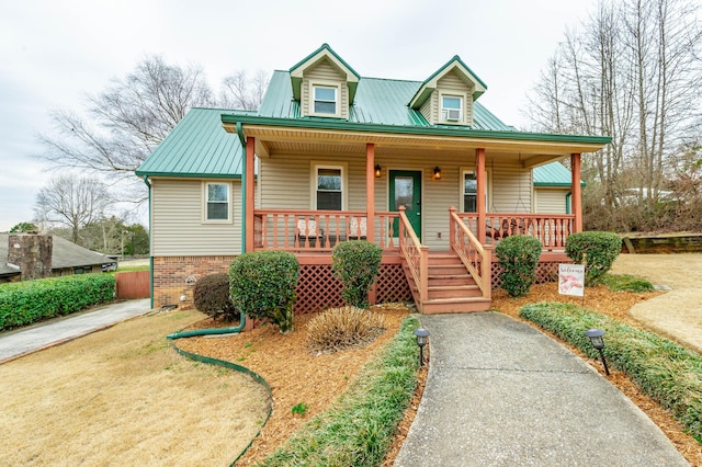 view of front of home with covered porch, metal roof, and brick siding