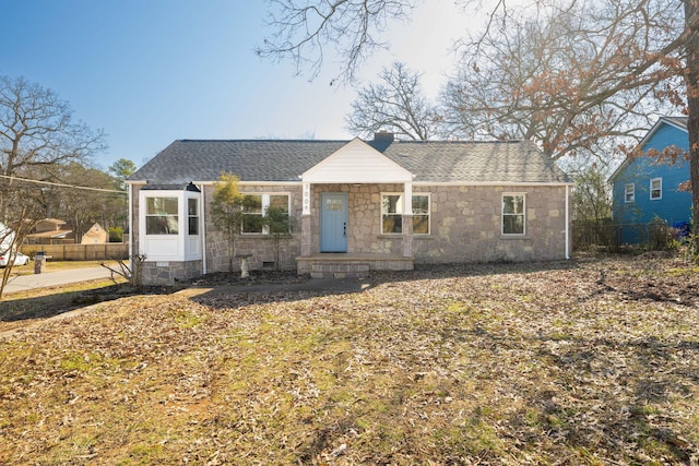 view of front of property with stone siding, roof with shingles, fence, and a chimney