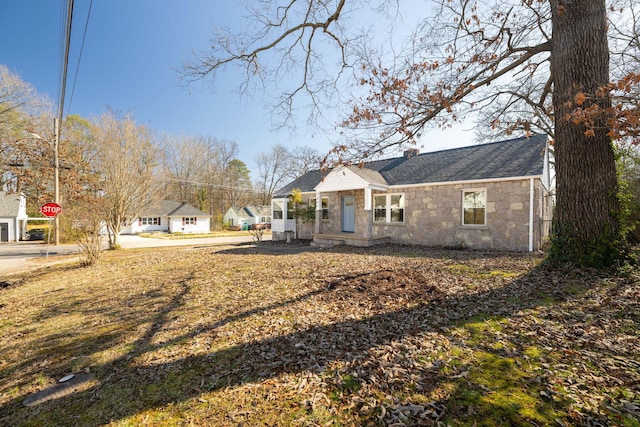 view of front of home featuring stone siding, a chimney, and a front lawn