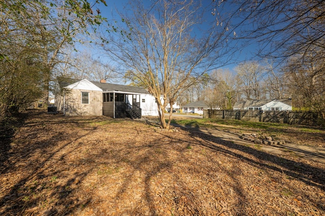 back of house with a chimney and fence