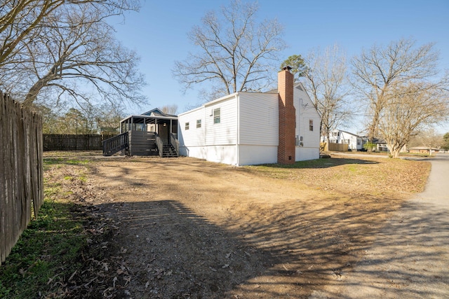 view of side of home featuring fence and a chimney