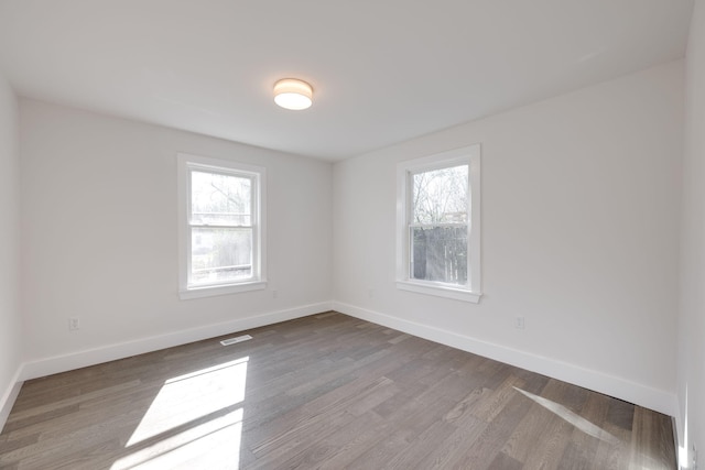 empty room with light wood-type flooring, visible vents, and baseboards