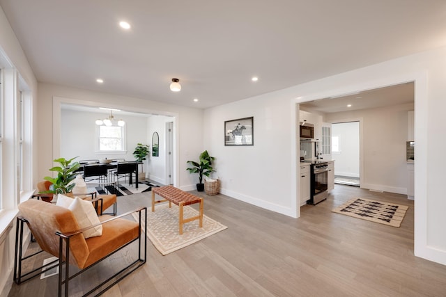 living room featuring baseboards, an inviting chandelier, light wood-style flooring, and recessed lighting