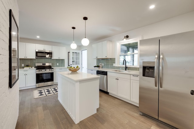 kitchen with white cabinets, appliances with stainless steel finishes, light countertops, and a center island