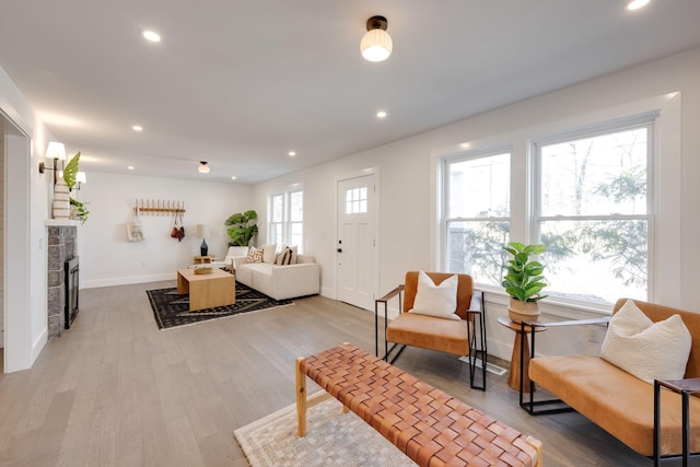 living room featuring baseboards, a tiled fireplace, light wood-style flooring, and recessed lighting