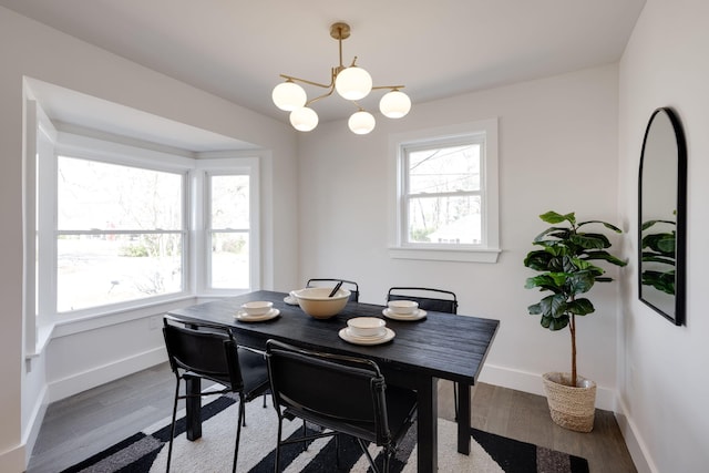 dining space with a chandelier, wood finished floors, and baseboards