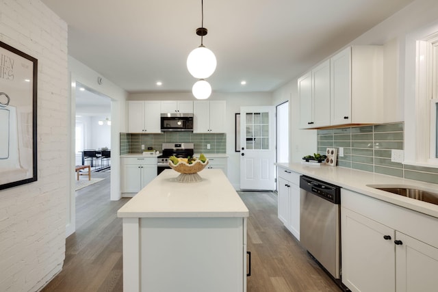 kitchen featuring white cabinetry, stainless steel appliances, light countertops, and decorative light fixtures