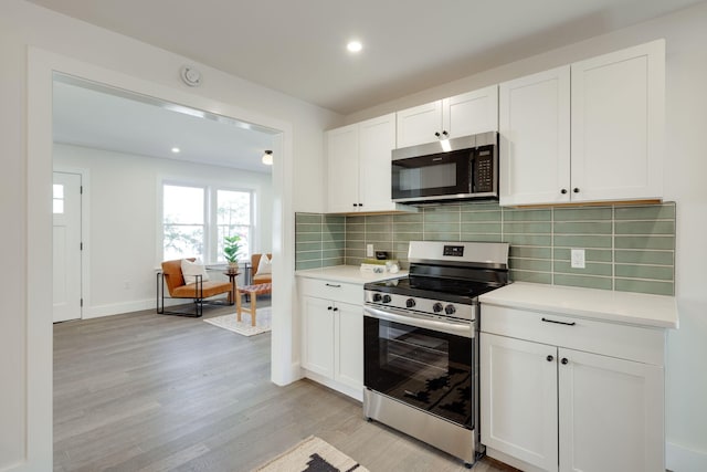 kitchen with appliances with stainless steel finishes, light countertops, light wood finished floors, and white cabinetry