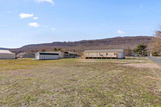 view of yard featuring fence, a mountain view, and an outdoor structure