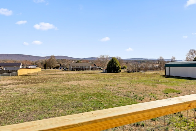 view of yard with a rural view, fence, and a mountain view