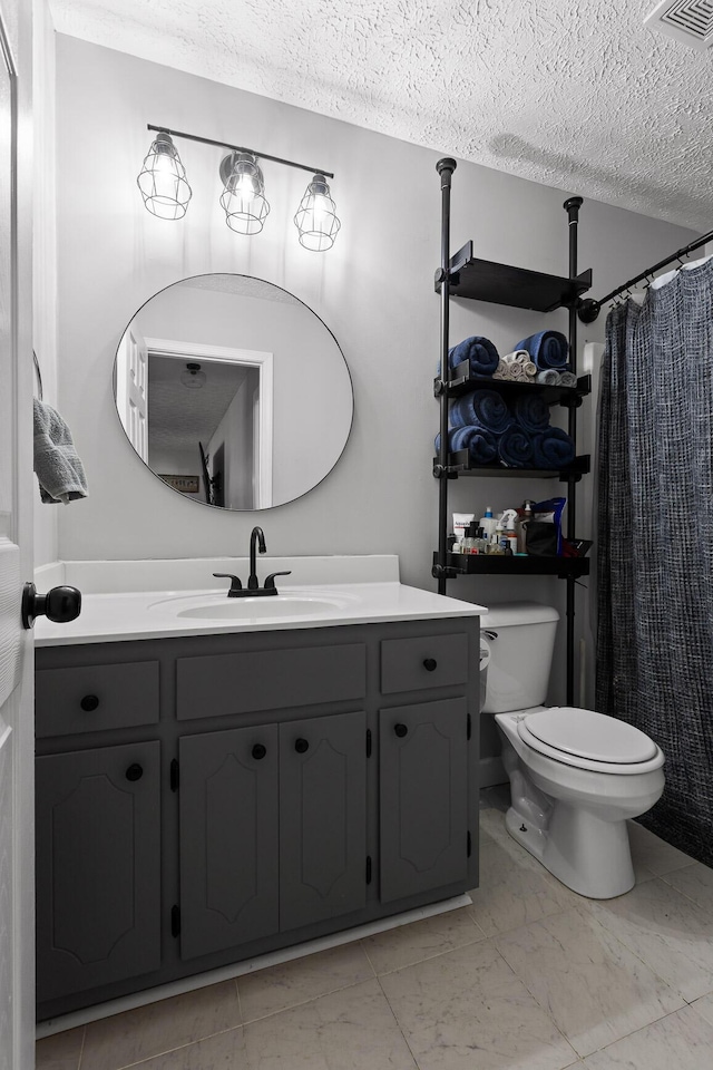 bathroom with toilet, marble finish floor, a textured ceiling, and vanity