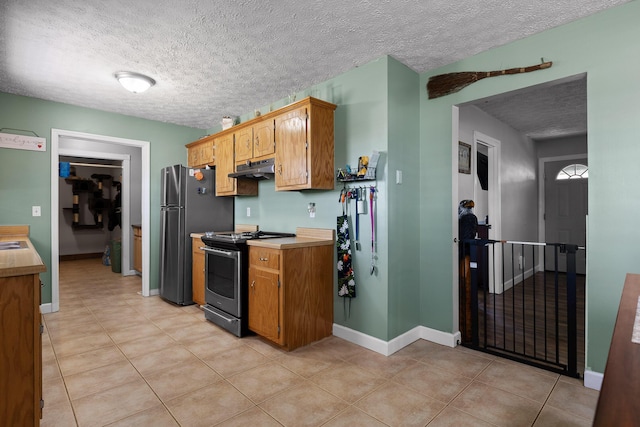 kitchen with light tile patterned floors, stainless steel appliances, light countertops, and under cabinet range hood