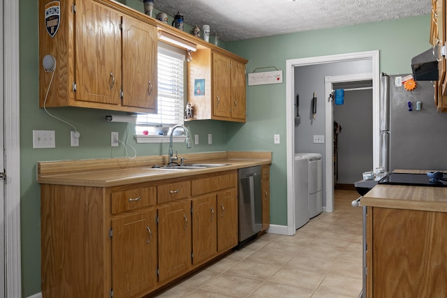 kitchen with light countertops, appliances with stainless steel finishes, a sink, a textured ceiling, and separate washer and dryer