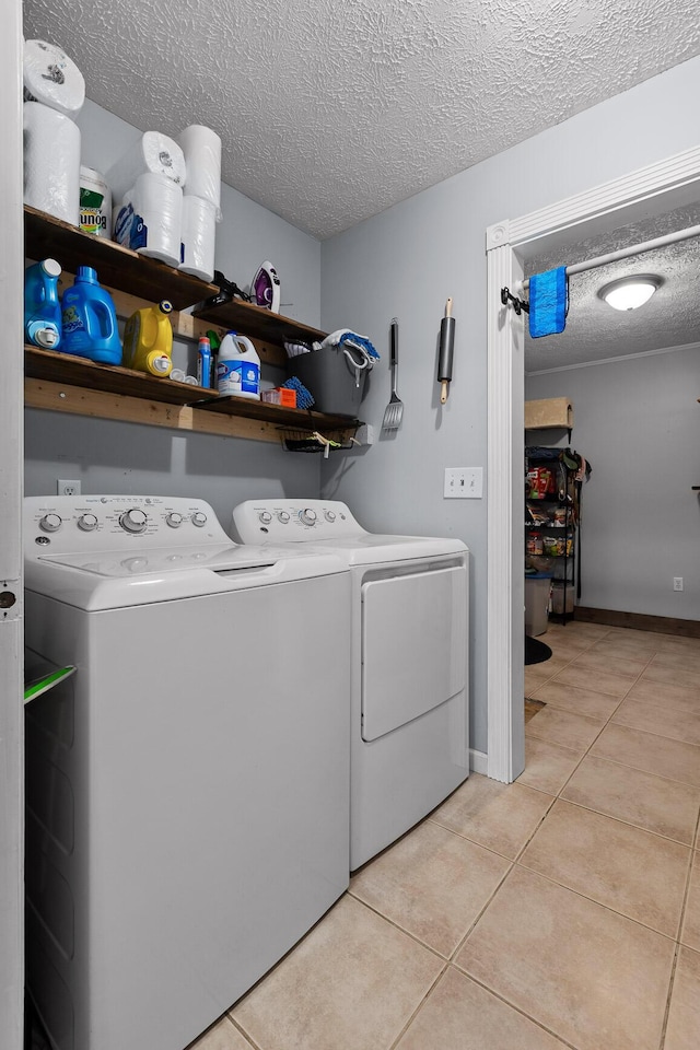 clothes washing area with laundry area, light tile patterned flooring, a textured ceiling, and independent washer and dryer