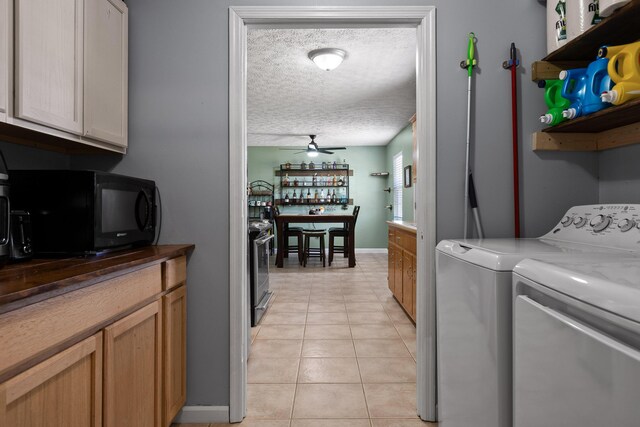 washroom featuring a textured ceiling, ceiling fan, light tile patterned floors, baseboards, and independent washer and dryer