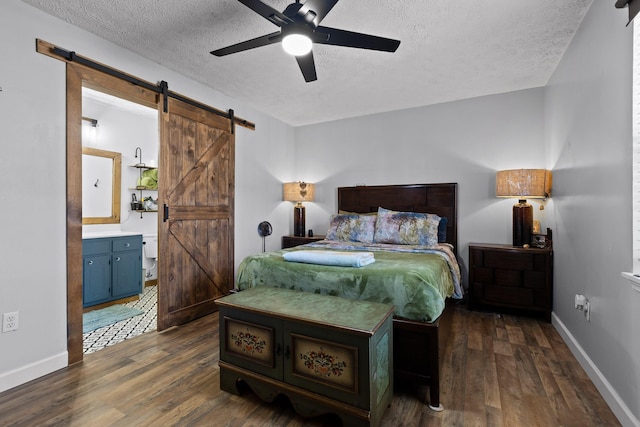 bedroom featuring dark wood finished floors, a textured ceiling, baseboards, and a barn door