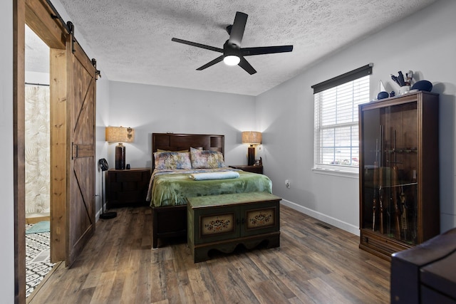 bedroom featuring a textured ceiling, a barn door, and wood finished floors