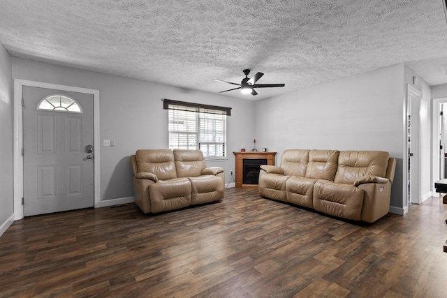 living room with dark wood-style floors, a textured ceiling, a fireplace, and baseboards