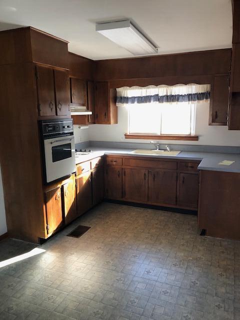 kitchen with white oven, light countertops, visible vents, a sink, and dark brown cabinetry