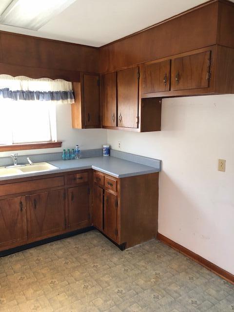 kitchen with light floors, baseboards, light countertops, and a sink