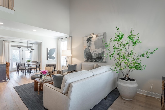 living area featuring light wood-style floors, recessed lighting, a towering ceiling, and baseboards