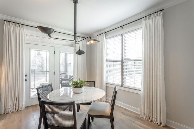 dining area featuring light wood-style floors, baseboards, and ornamental molding