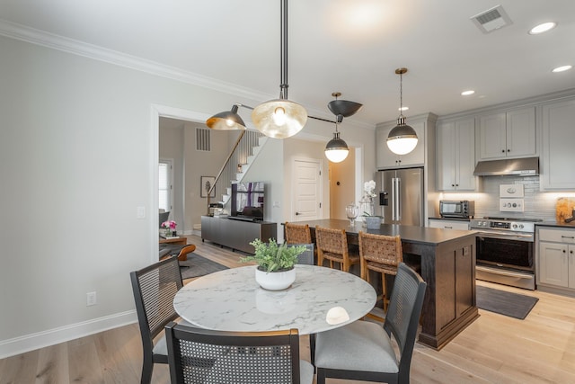 dining area featuring visible vents, baseboards, stairs, ornamental molding, and light wood finished floors