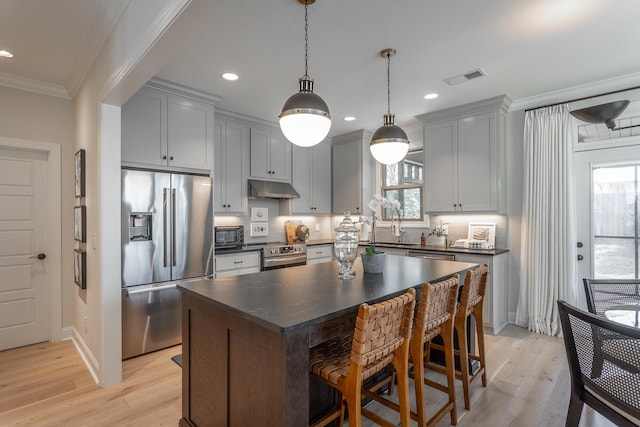 kitchen with dark countertops, visible vents, appliances with stainless steel finishes, ornamental molding, and under cabinet range hood