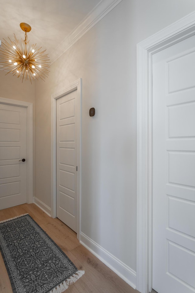 entryway with ornamental molding, light wood-style flooring, baseboards, and an inviting chandelier